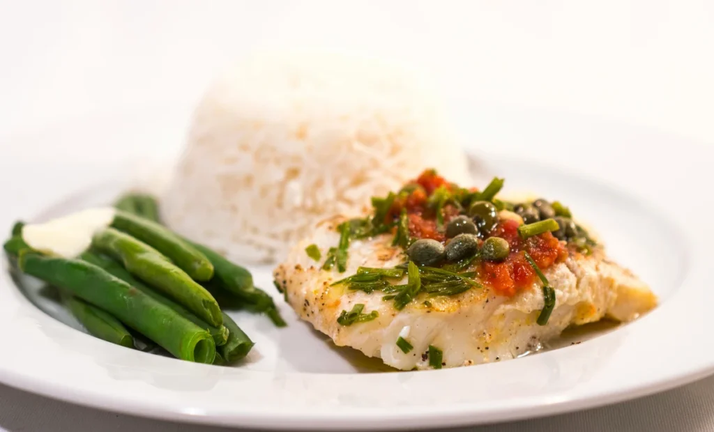 Frisk hvid torskefilet stegt med citron og friske krydderurter, serveret med friske bønner og ris