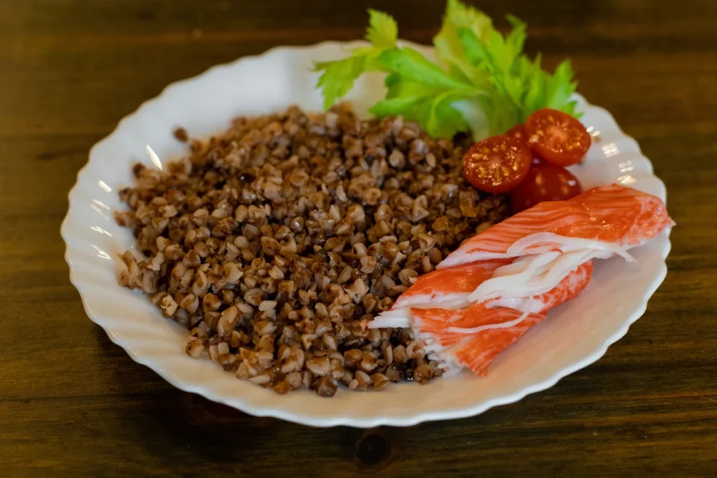 Tilberedt boghvede på en tallerken med frisk laks, tomat og salat