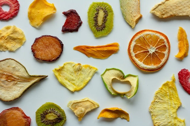 Hjemmelavede rodfrugtchips i forskellige farver spredt på bagepapir.